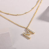 Close-up of double-layer M pendants with moissanite stones on gold chains