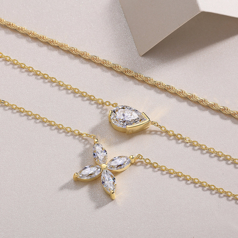 Close-up of gold-tone layered necklace with three chains and pear-cut crystal charms