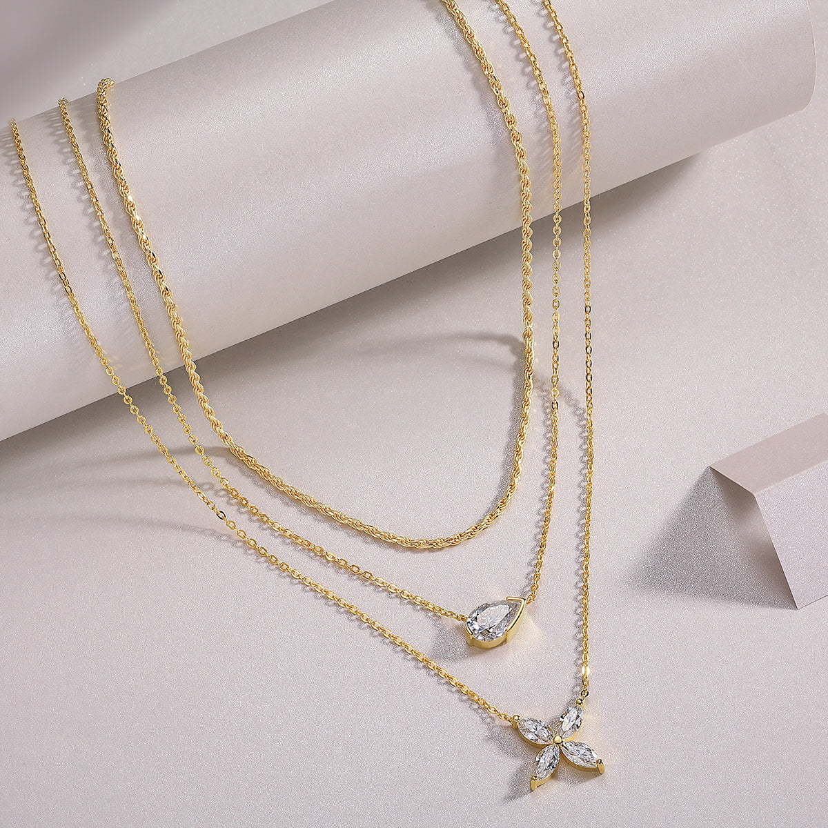 Layered gold-tone necklace set on display: pear-cut stones with small center pendant