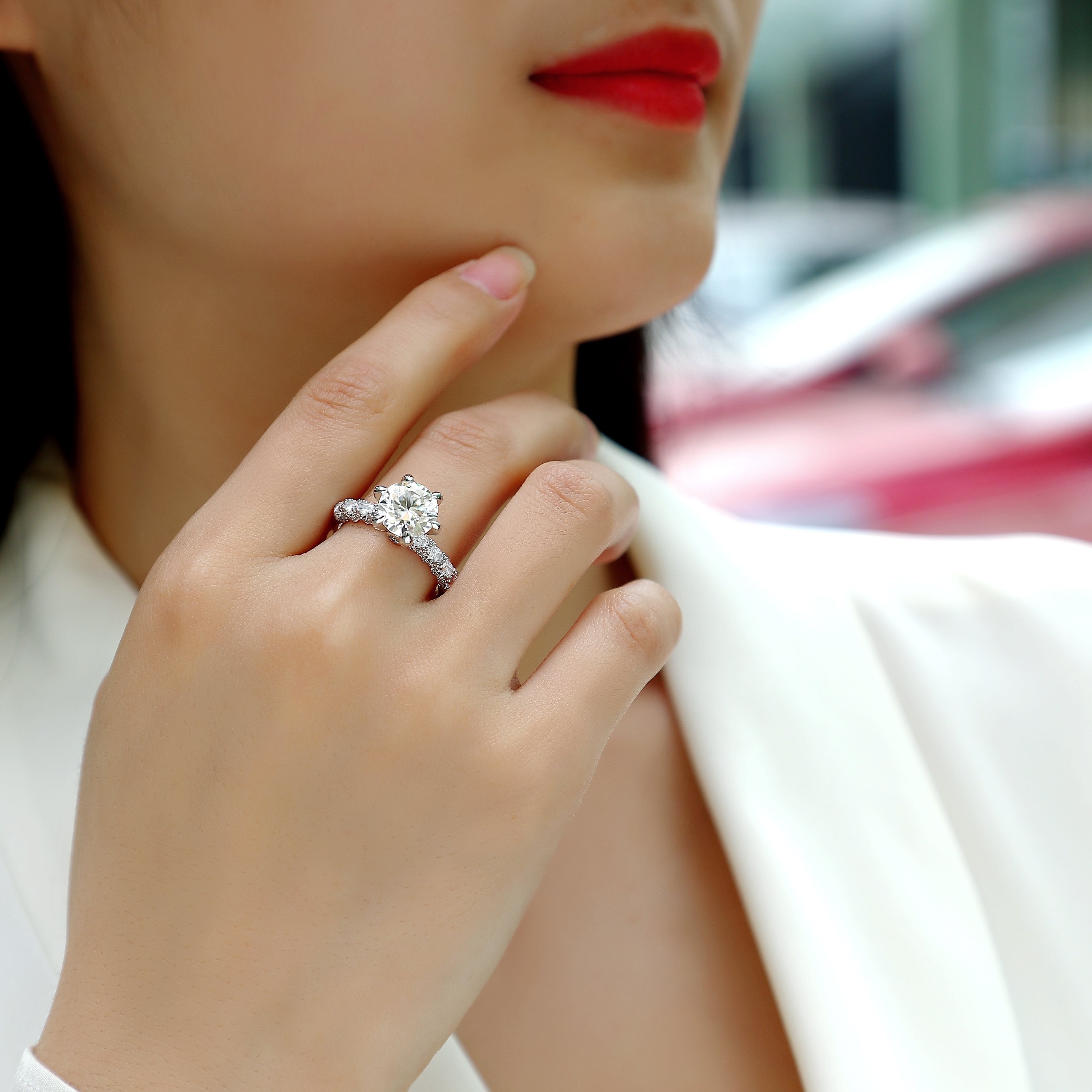 Ring on hand: round center moissanite with pavé halo and six-prong setting
