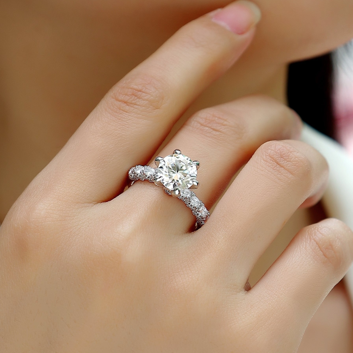 Moissanite engagement ring on fingers, round center stone with pavé band texture