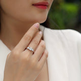 Round three-stone engagement ring on finger, white gold vermeil, prong-set moissanite