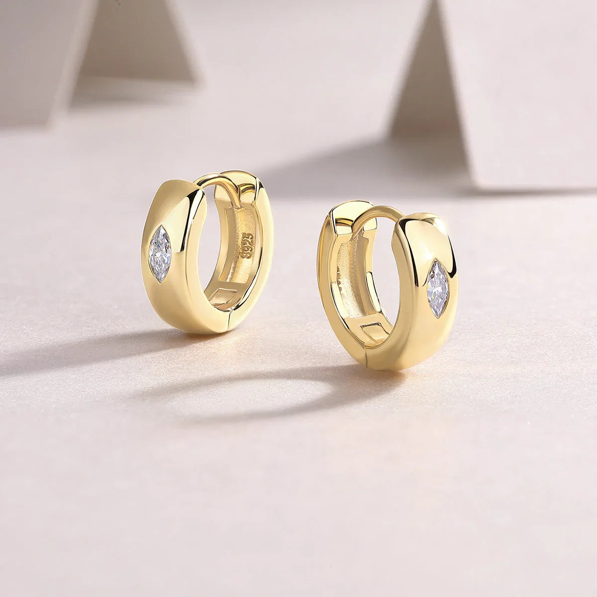 Yellow gold vermeil huggie hoop earrings with bezel-set marquise moissanite, angled