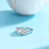 White gold-plated three-round moissanite ring with three round stones, side angle