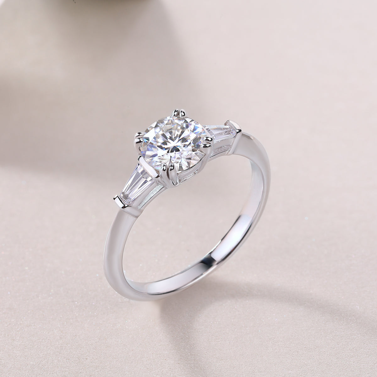 White metal three-stone ring with round center and baguette side stones
