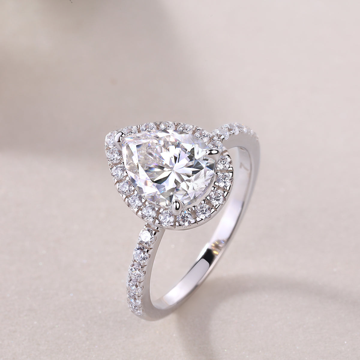 Side view of pear-cut halo engagement ring with sparkling pavé stones, white gold vermeil
