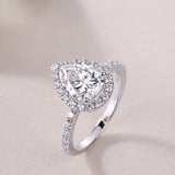 Side view of pear-cut halo engagement ring with sparkling pavé stones, white gold vermeil