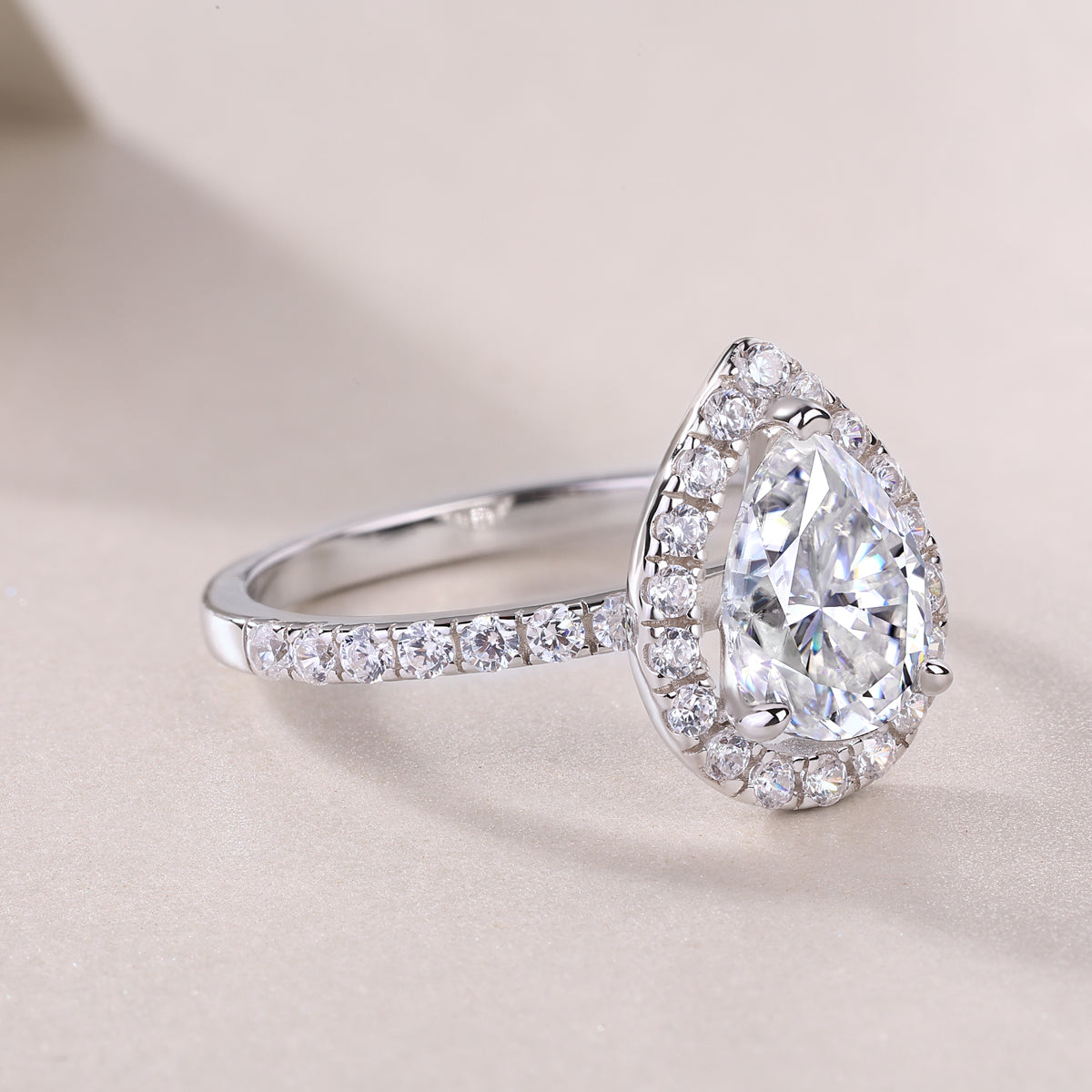 Pear-cut halo engagement ring profile with full pavé band, white gold vermeil