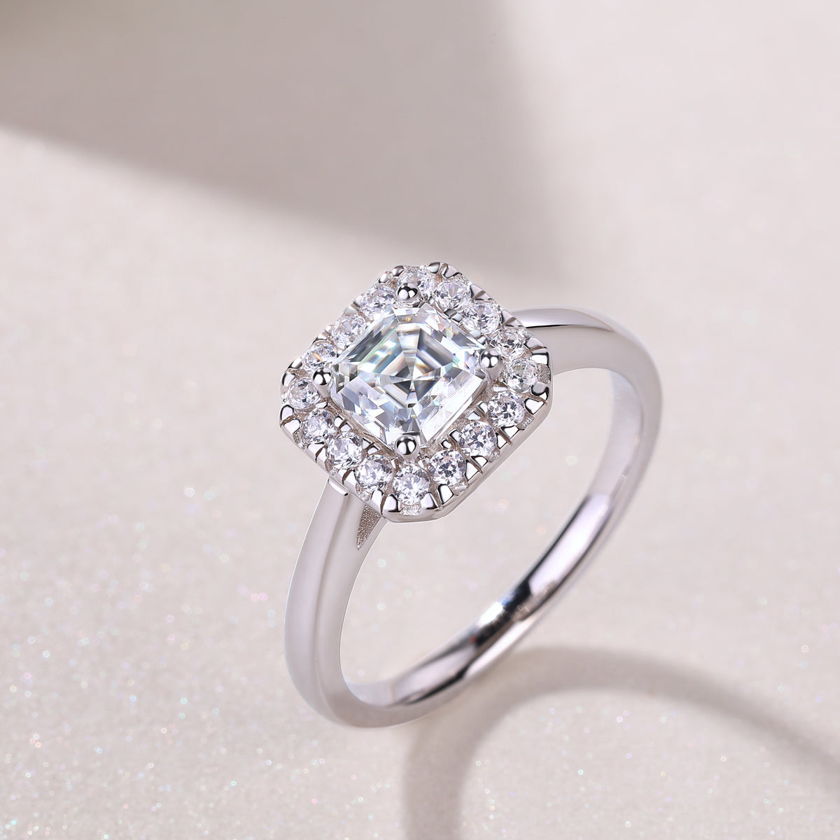 Close-up of Asscher-cut moissanite ring with halo stones in white metal