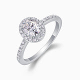 Angled view of oval Moissanite pavé halo engagement ring, white gold vermeil