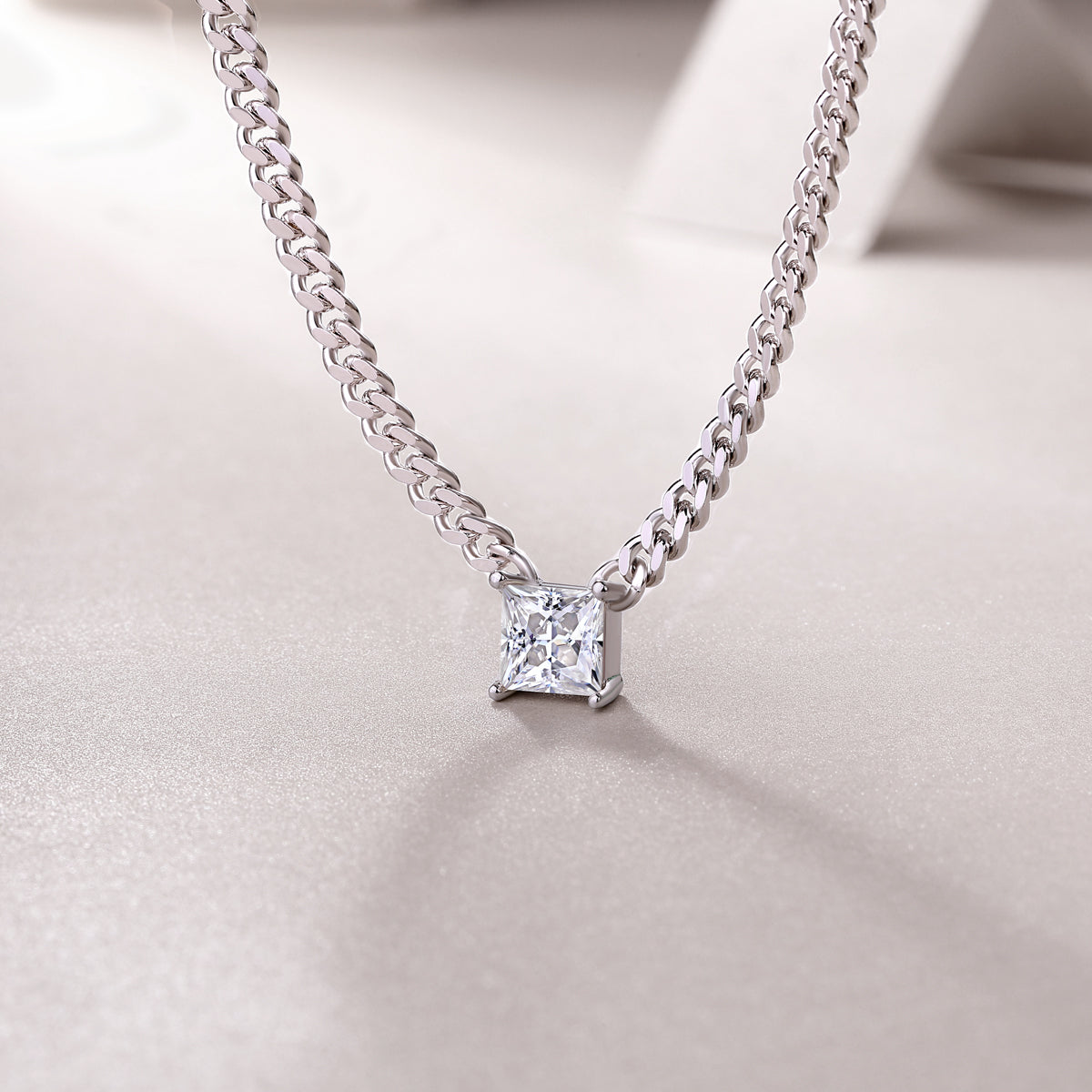 Square moissanite pendant centered on Cuban link chain with prong-set corners