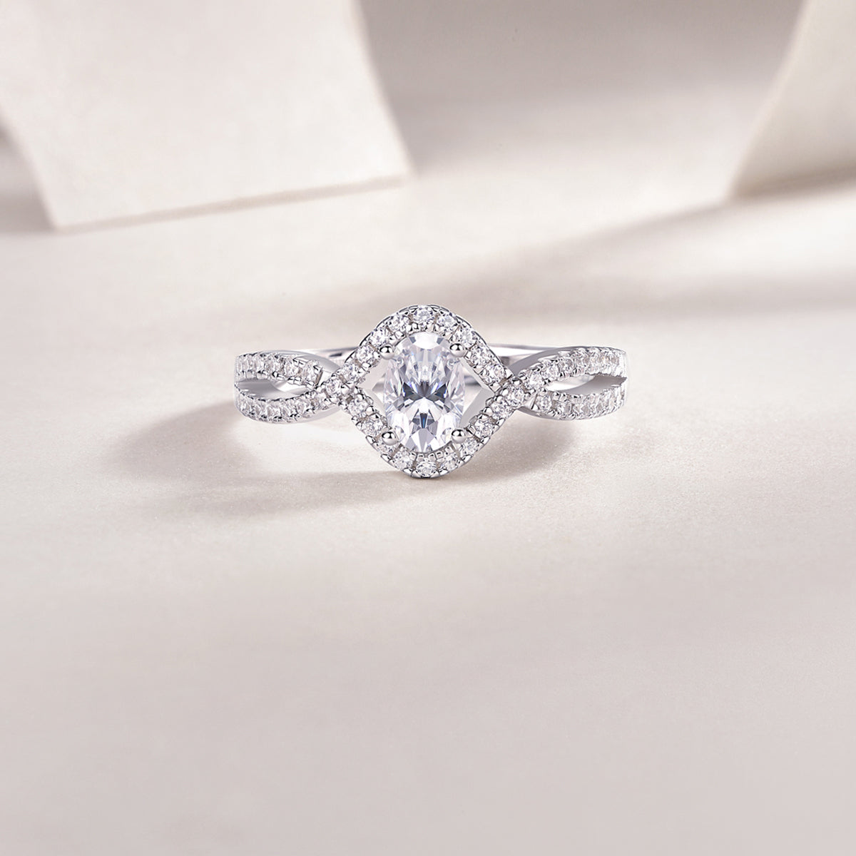 Close-up of oval center moissanite with pavé halo and twisted split shank, white gold vermeil