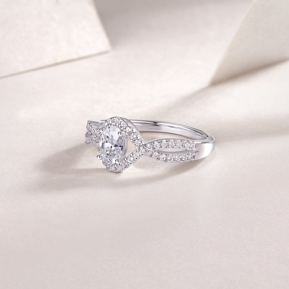 Angled view of oval halo moissanite ring with twisted pavé band, white gold vermeil