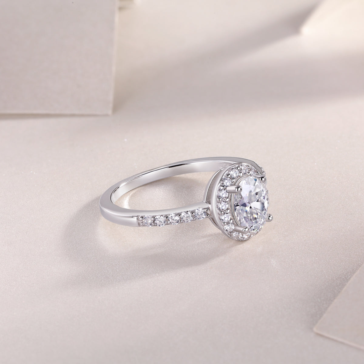 Three-quarter view of oval Moissanite pavé engagement ring, white gold vermeil