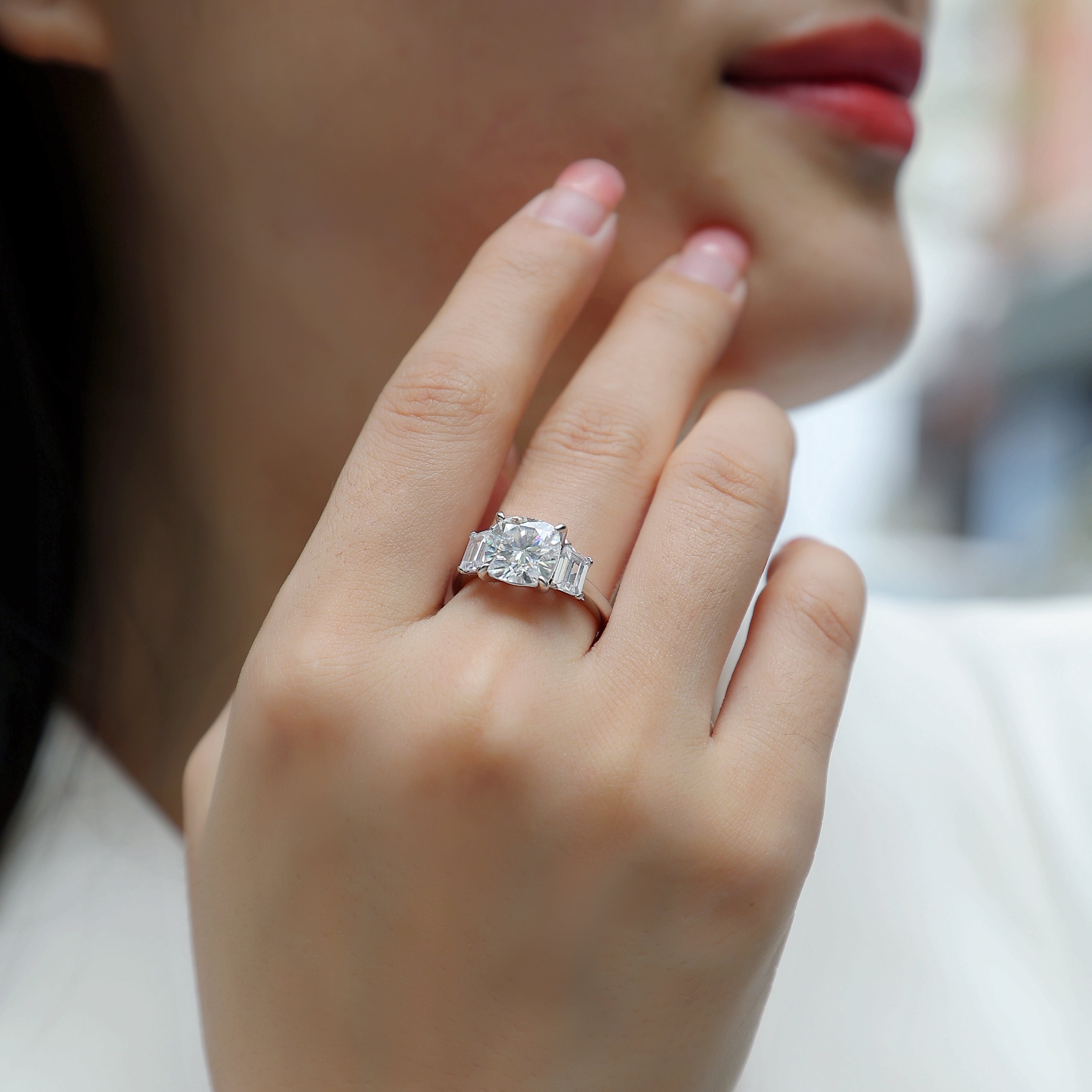 Engagement ring on hand with cushion-cut center stone and baguette side stones