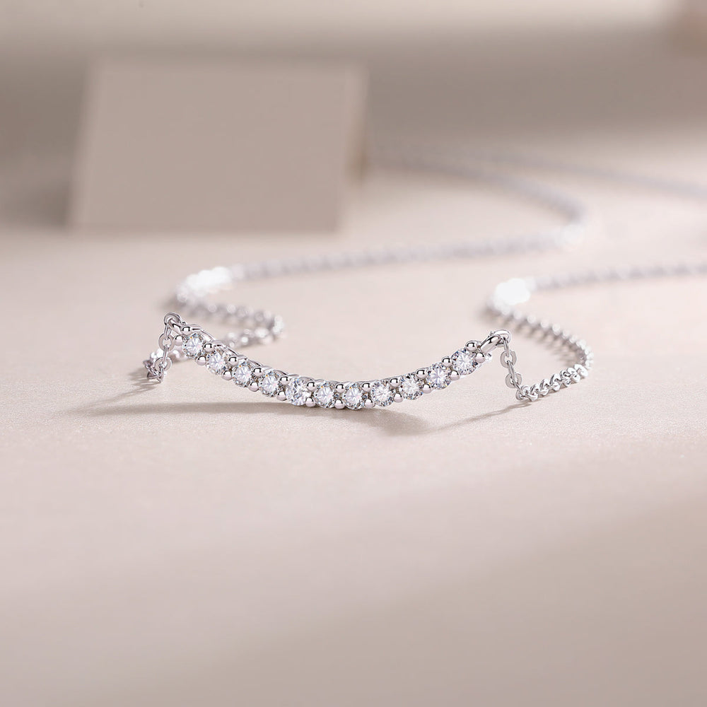 Curved bar moissanite smile necklace side view with pavé-like round stone settings