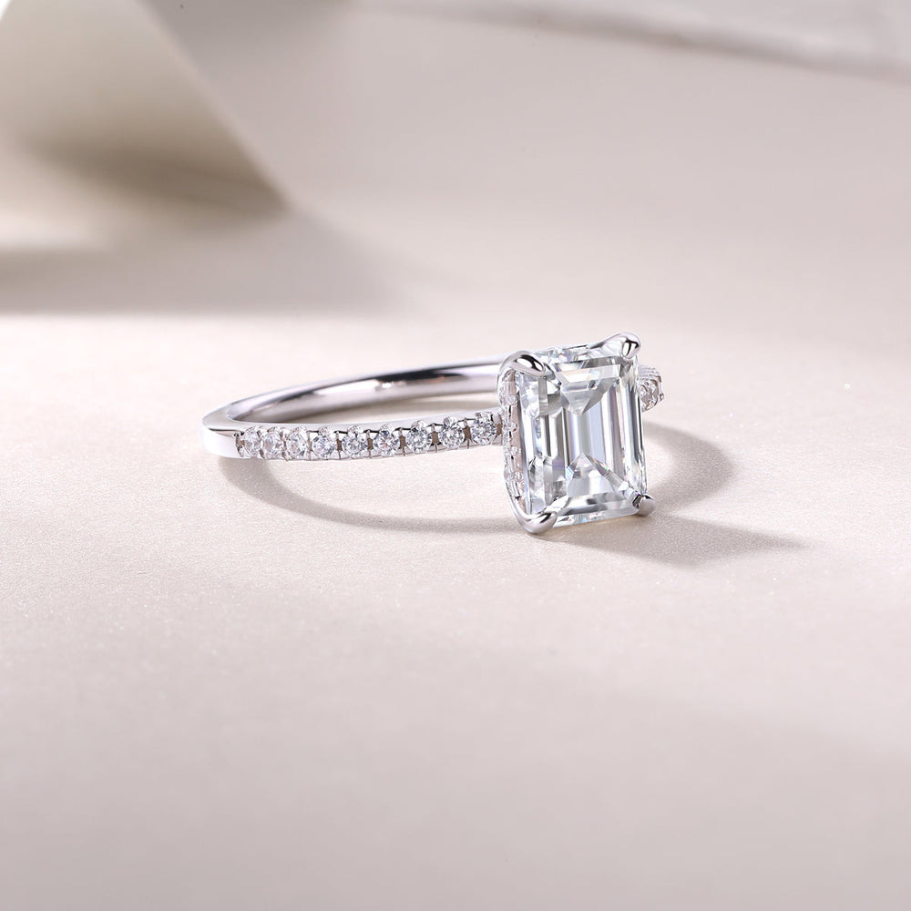 Profile view of pavé engagement ring with emerald-cut center stone, white gold vermeil