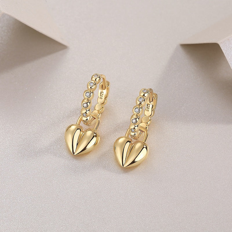 Close-up: yellow gold vermeil beaded huggie earrings with heart charm and stones