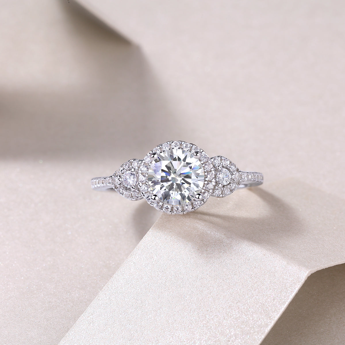 Round halo cluster ring with prong-set center and pear-shaped side stones