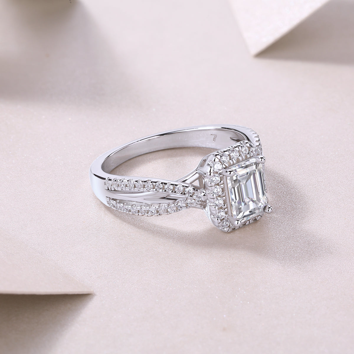 Side profile of emerald-cut halo moissanite ring, twisted pavé shank, white metal