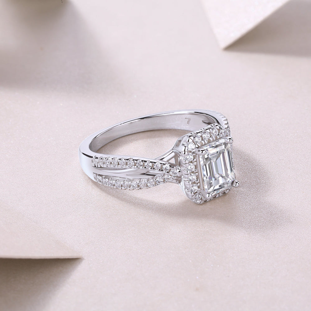 Side profile of emerald-cut halo moissanite ring, twisted pavé shank, white metal