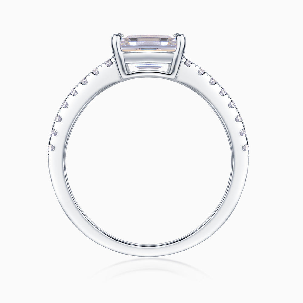 Top view of emerald-cut moissanite ring with pavé shoulders, white gold tone