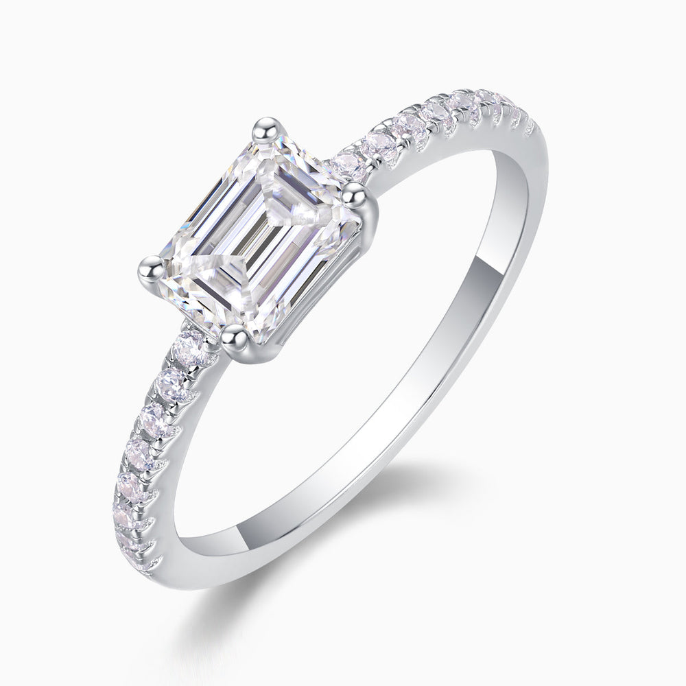 Side view of emerald-cut moissanite ring with pavé shoulders, white gold tone band