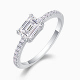 Side view of emerald-cut moissanite ring with pavé shoulders, white gold tone band