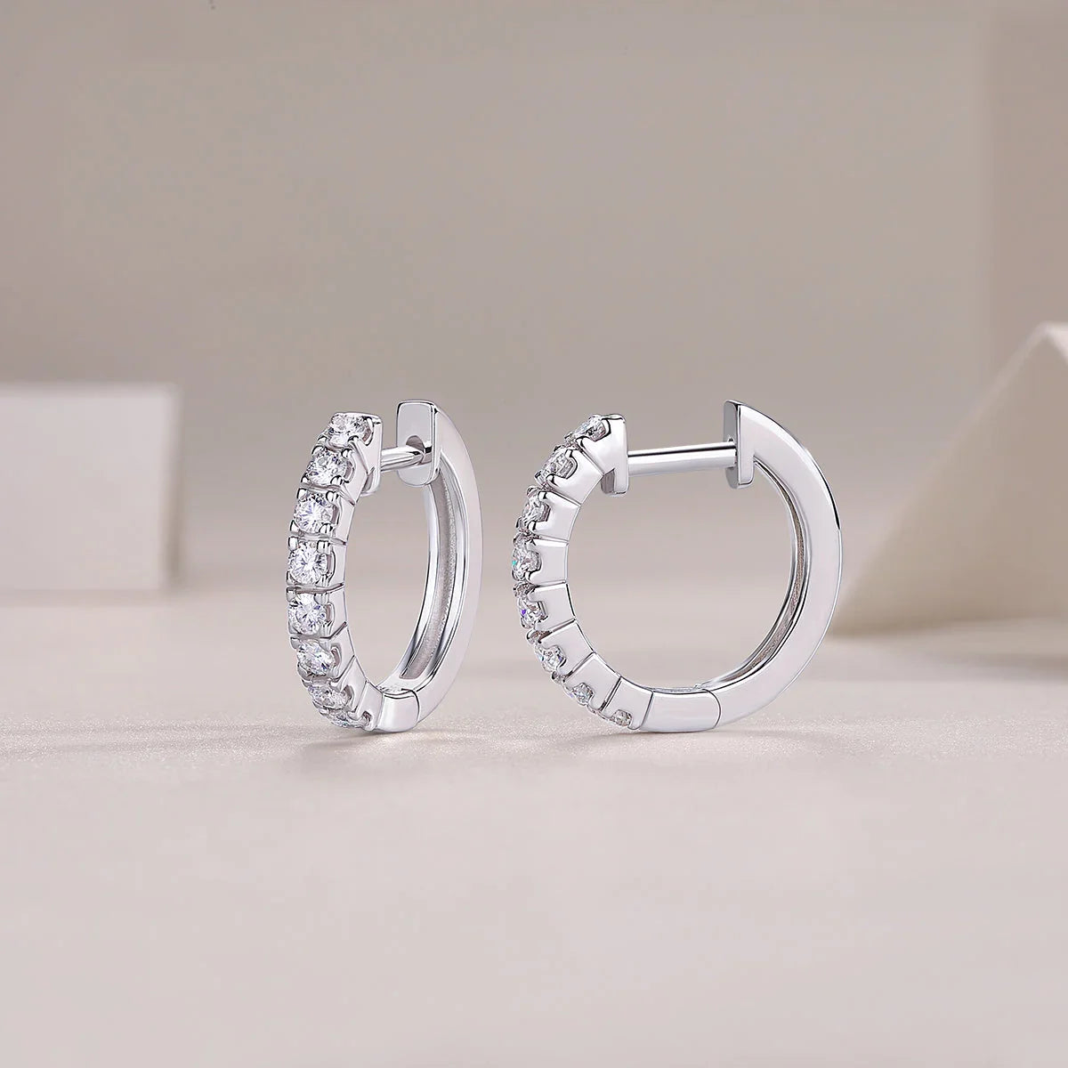 Moissanite huggie hoop earrings in shared prong setting, side view with hinge post