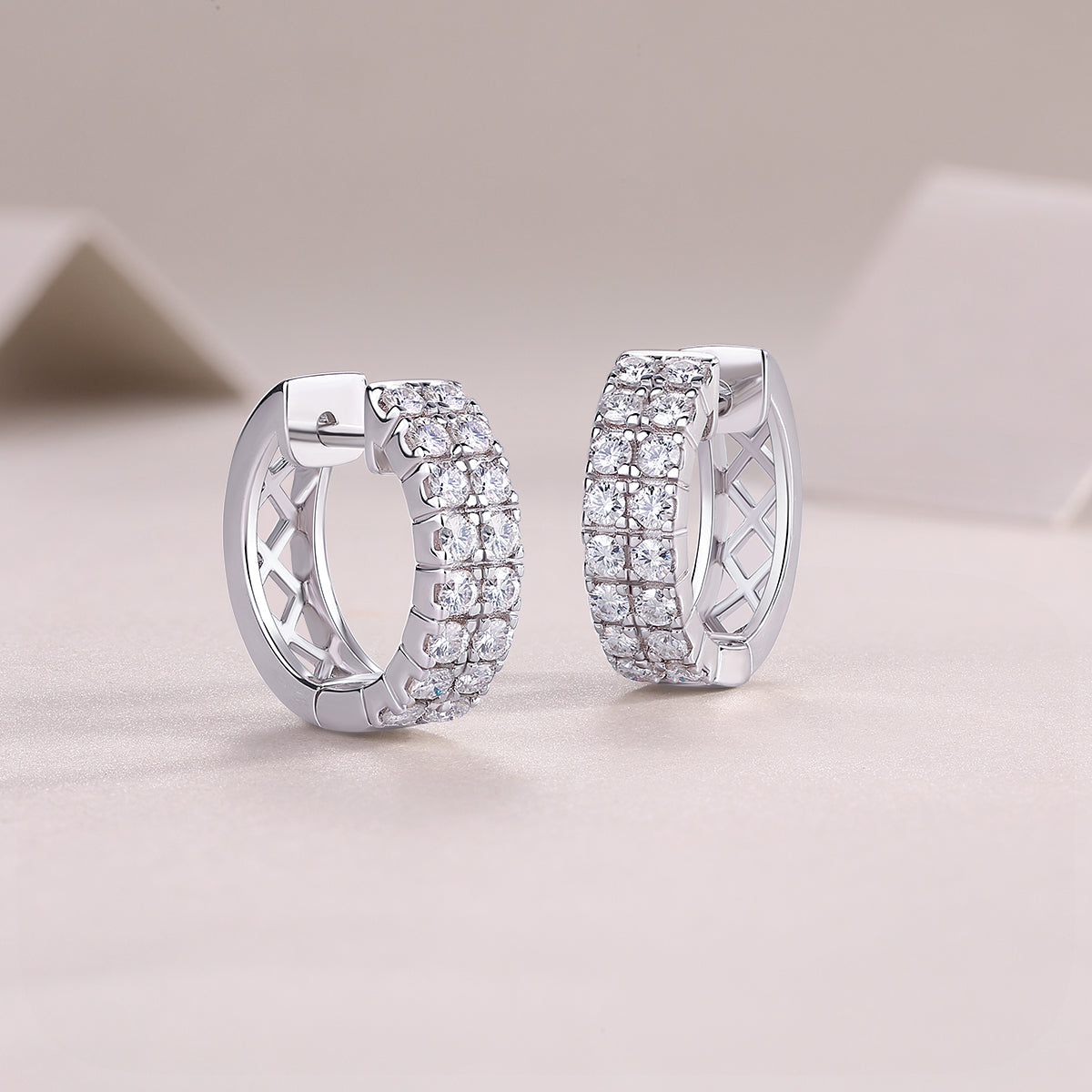 Huggie hoop earrings showing hinge post and double-row moissanite pavé band