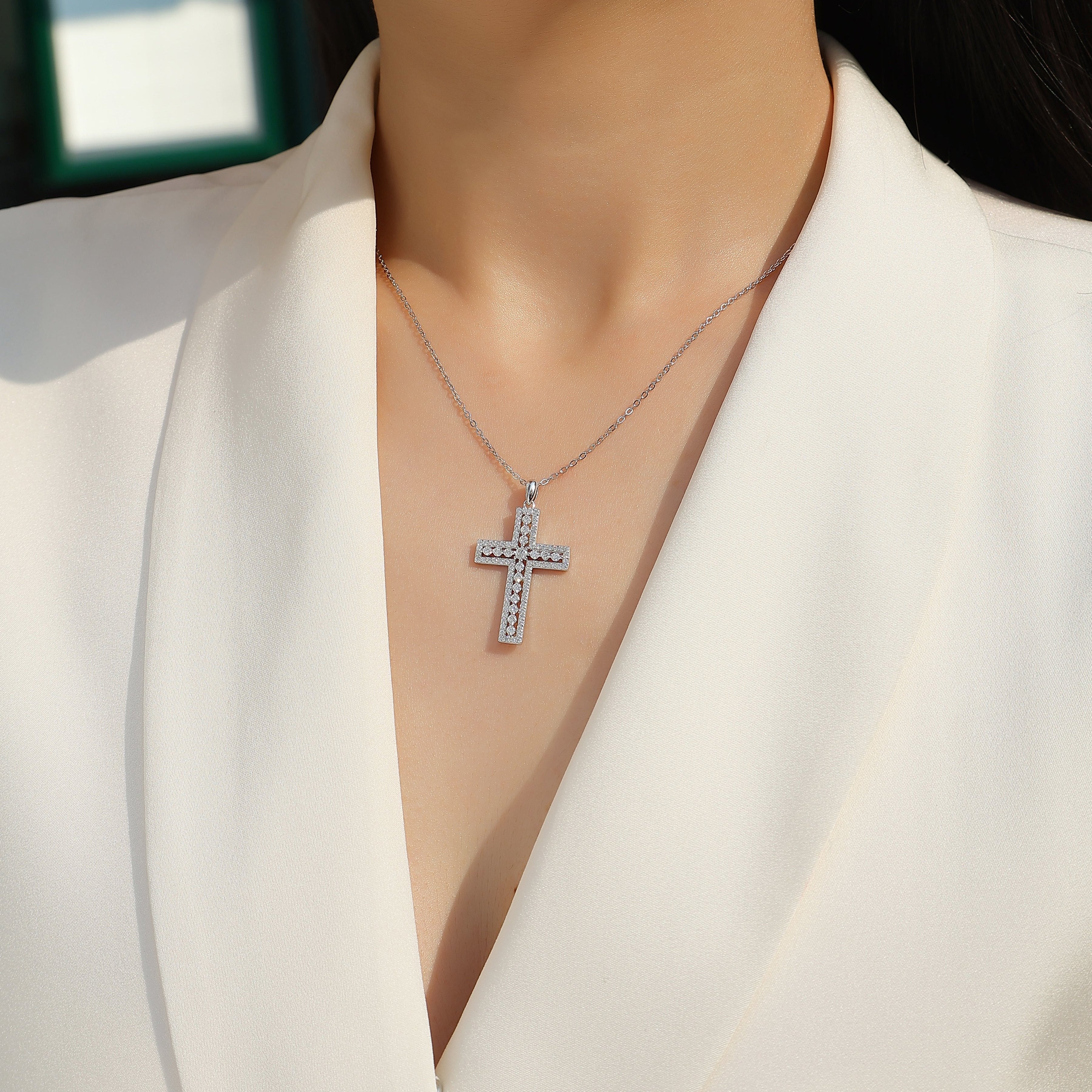 White gold vermeil pavé cross pendant on a chain, close view at neckline