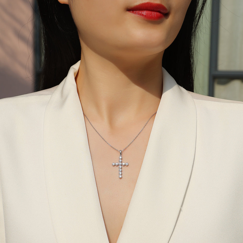 Moissanite cross pendant necklace with round stones on fine chain, worn at neckline