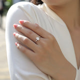 Solitaire emerald-cut moissanite ring on finger, white gold vermeil band