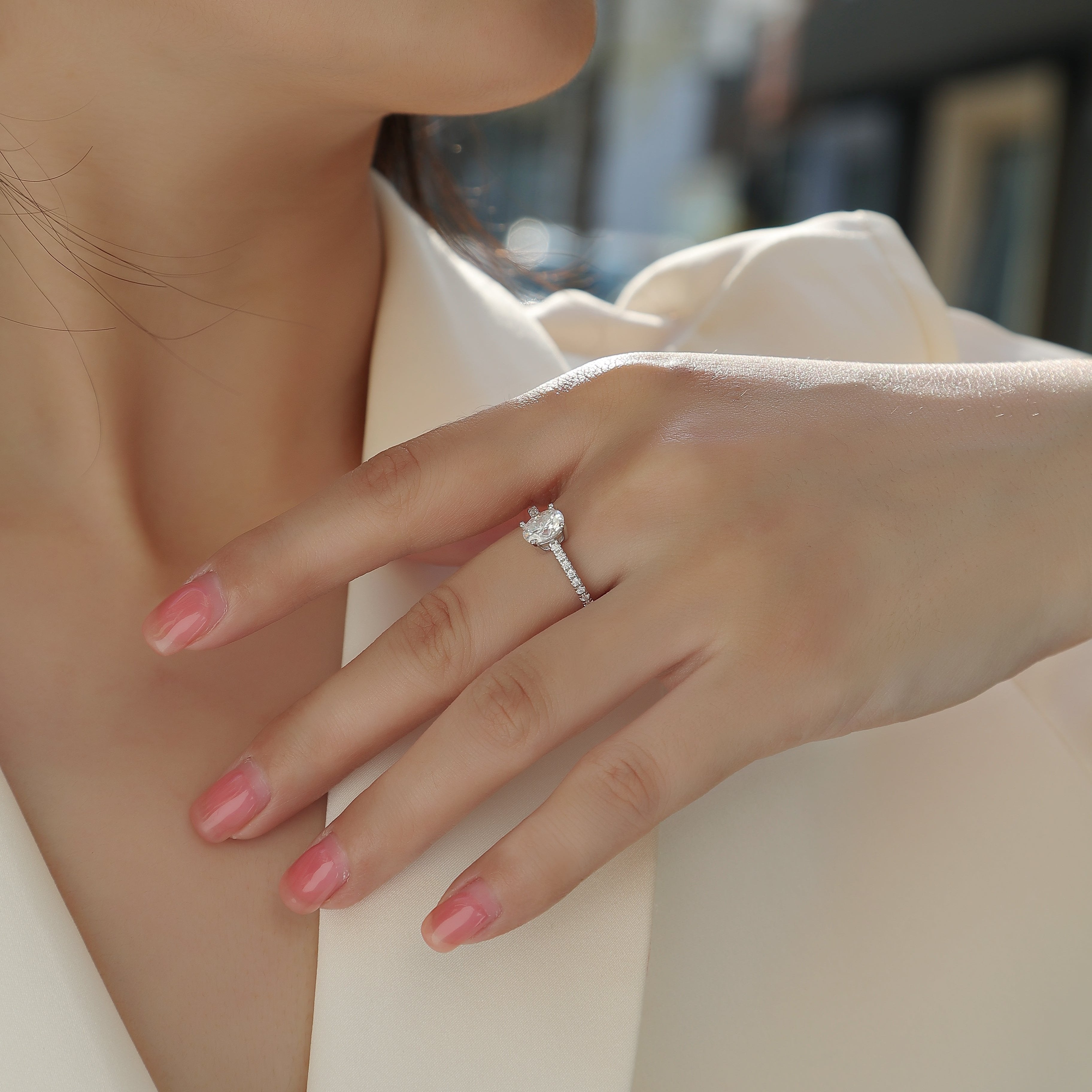 Oval-cut moissanite engagement ring on hand, pavé band and prong-set center stone