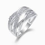 Angled view of crossover wide band ring with round prong-set moissanite and pavé