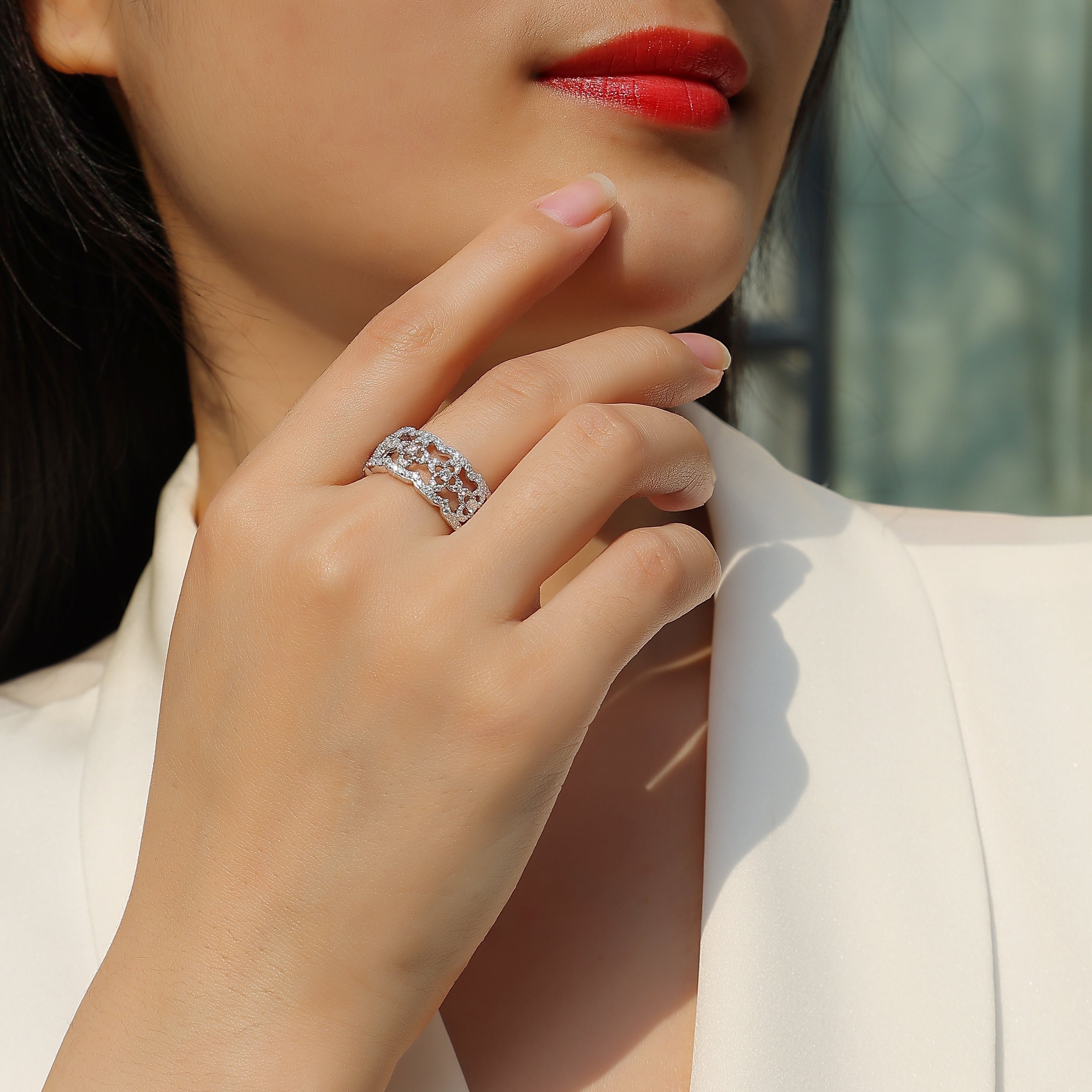 Moissanite band ring with hollow-cut design on finger; white gold vermeil
