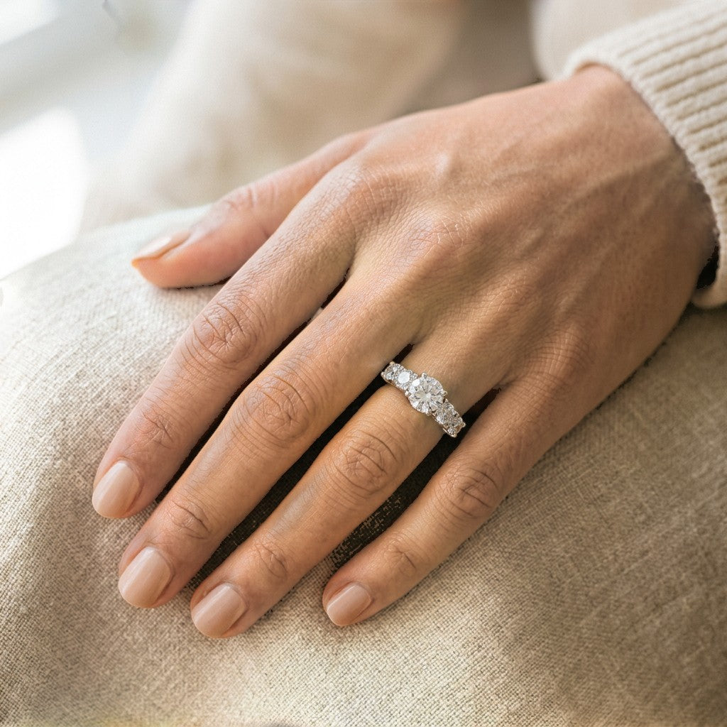 Five-stone moissanite ring on hand, slim band with sparkling center stone and side stones