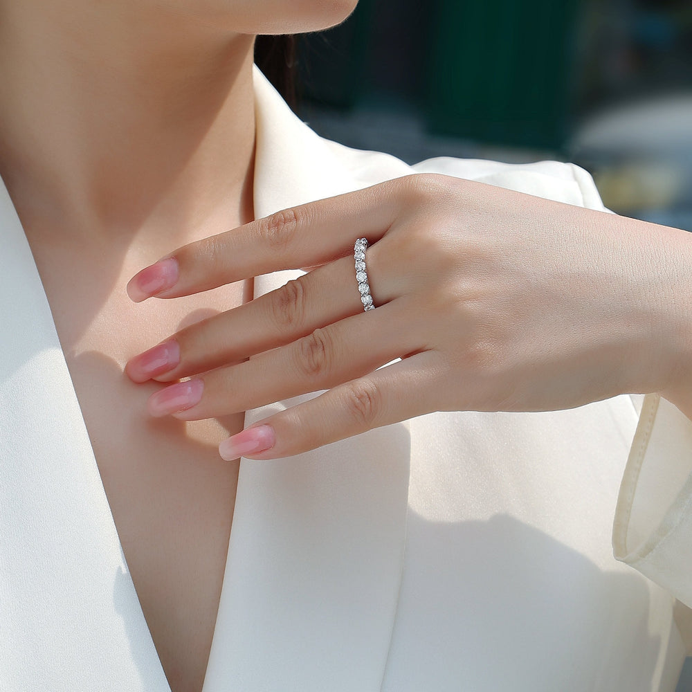 Pavé eternity ring with round moissanite stones worn on finger, white gold vermeil