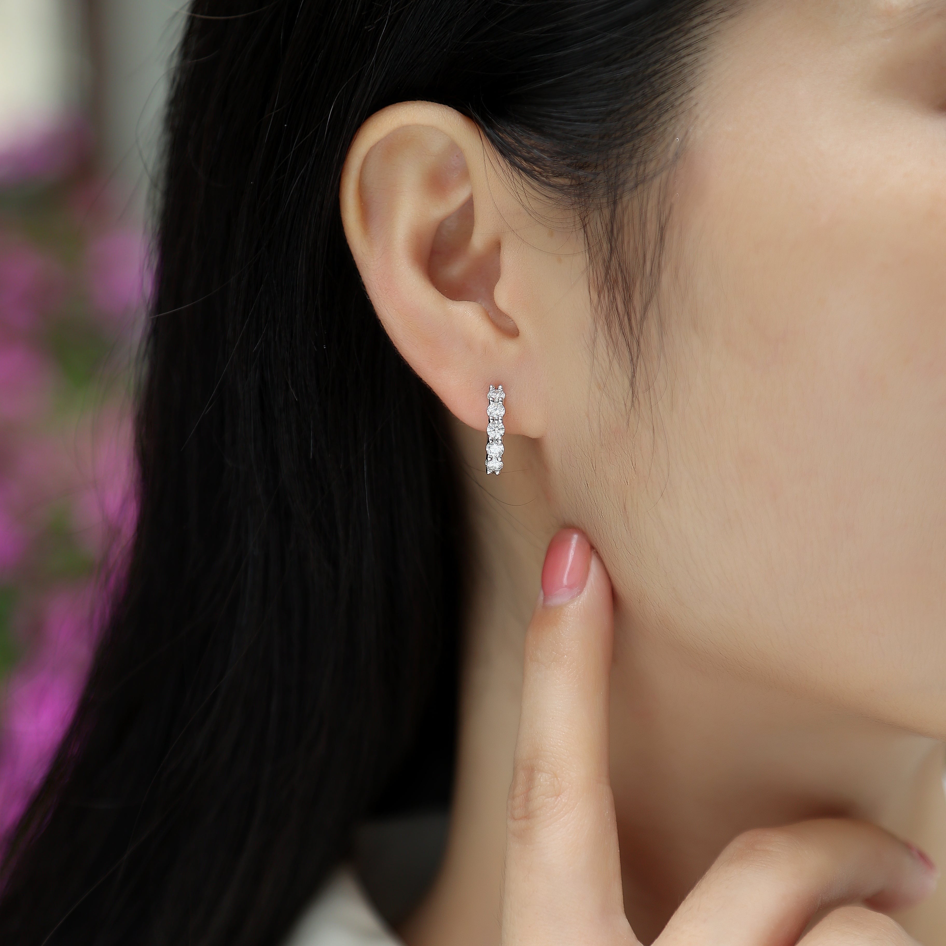 White gold vermeil hoop earrings with three round moissanite stones, worn on ear