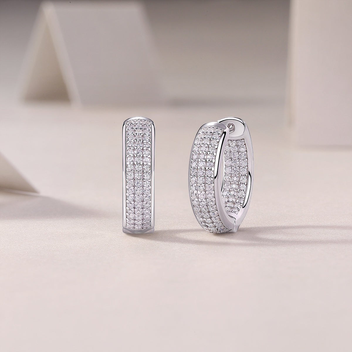 Moissanite huggie hoops, white gold vermeil, pavé stones with hinge detail, side view.