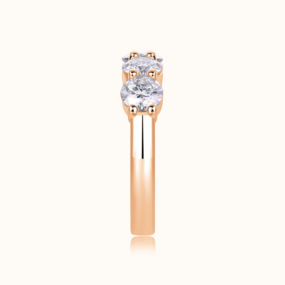 Rose gold five-stone moissanite wedding band with faceted oval center stone