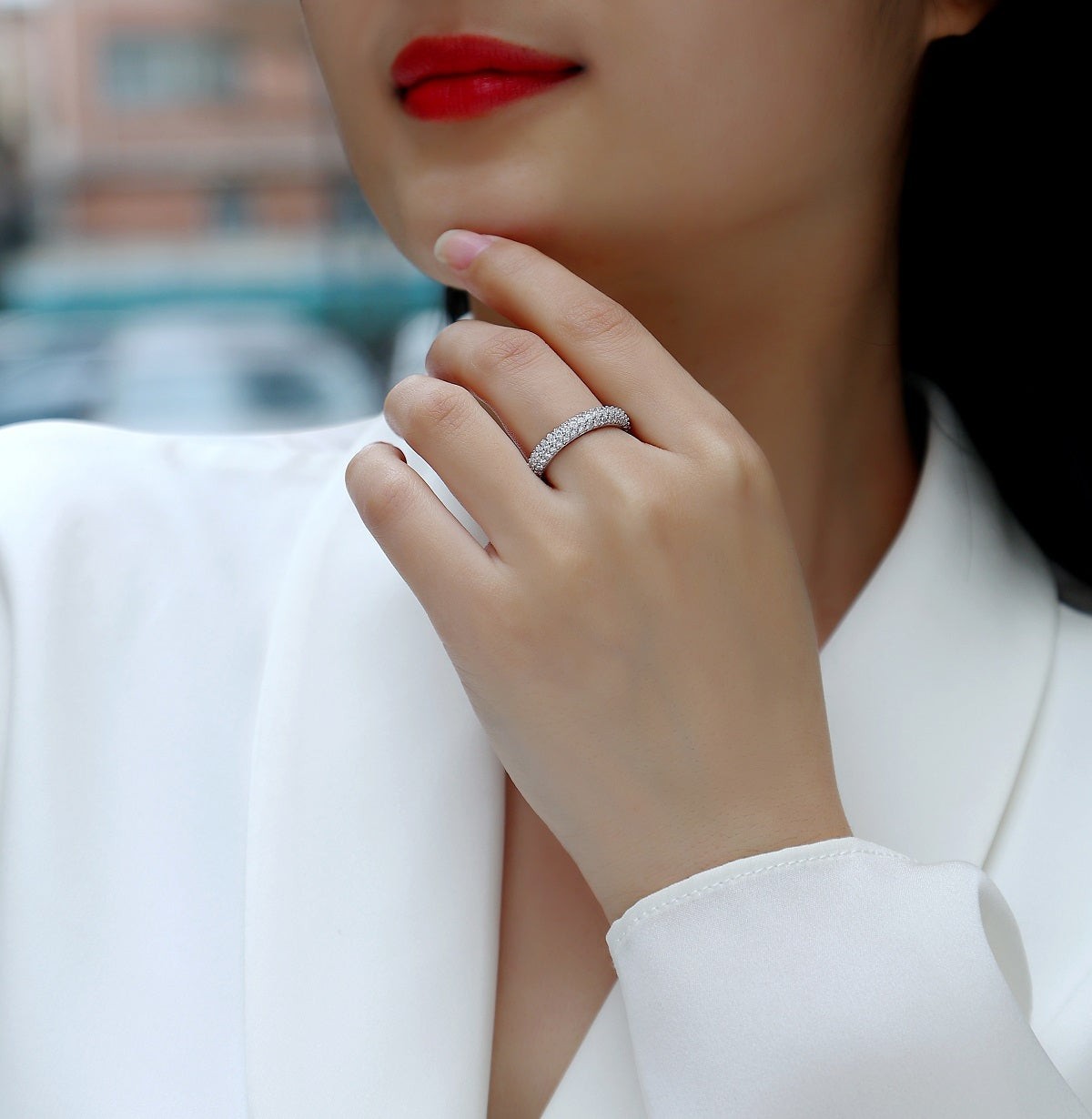 Triple-row pavé moissanite band ring on finger with bright stone setting.
