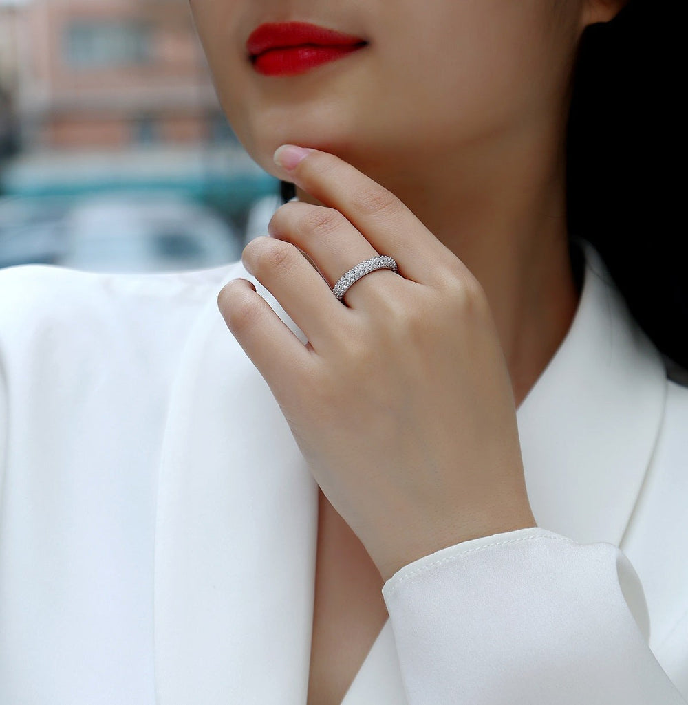 Triple-row pavé moissanite band ring on finger with bright stone setting.